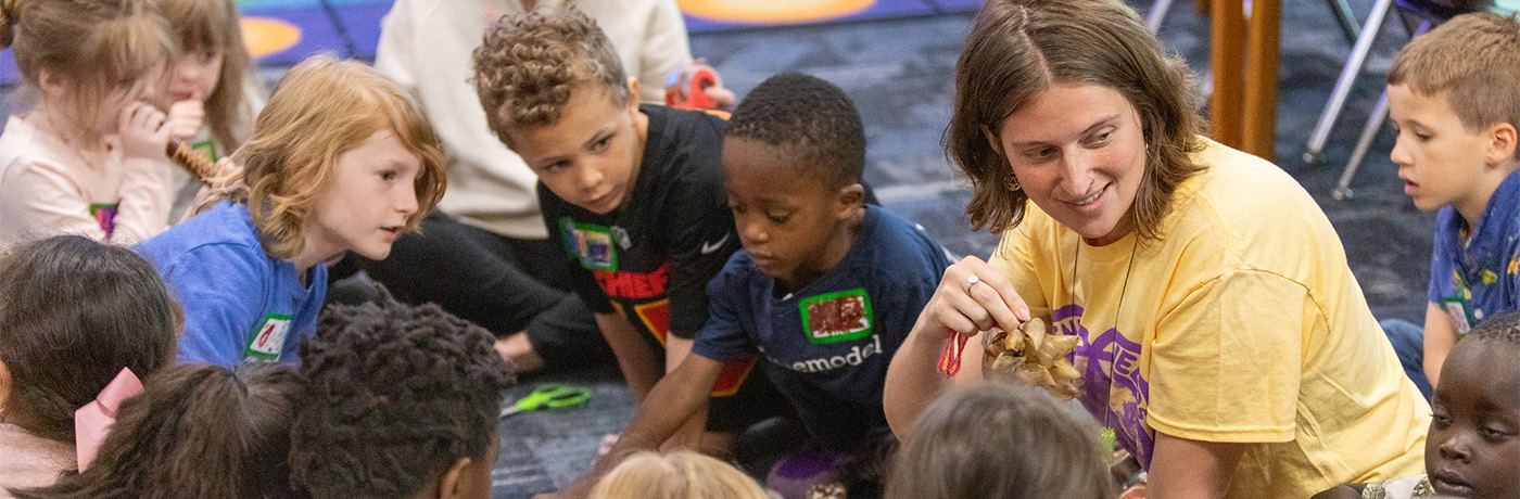 teacher doing show and tell with students sitting on the floor